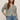 Woman wearing a striped sweater and jeans against a plain background