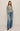 Woman wearing a striped sweater and blue jeans on a beige background