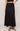 Person wearing a black long skirt on a plain background