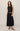 Woman wearing a black sleeveless top and black skirt on a beige background
