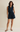 Woman wearing a navy sleeveless dress on a beige background