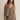 Woman wearing a brown vest and skirt set against a plain background