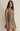 Woman wearing a sleeveless brown dress against a plain background