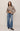 Person wearing a beige shirt and blue jeans on a plain background