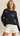 Woman wearing a navy sweater with white shell patterns on a beige background