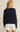 Person wearing a navy sweater with a logo on a beige background