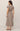 Woman wearing a long brown dress on a plain background