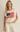 Woman wearing a cream-colored sleeveless top with an American flag design on a beige background