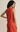 Woman wearing a red sleeveless top and pants against a beige background