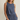 Woman wearing a blue sleeveless top and pants against a beige background