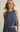 Woman wearing a sleeveless blue top and matching pants against a beige background