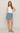 Woman wearing a white top and gray skirt on a plain background