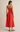 Woman wearing a strapless red dress on a beige background