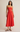 Woman wearing a strapless red dress against a beige background
