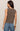 Woman wearing a brown sleeveless top and blue jeans on a beige background