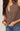 Brown knitted sleeveless top worn by a person with a neutral background