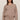 Woman wearing a brown sweater and pants on a beige background