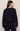 Person wearing a navy blue sweatshirt and pants on a beige background