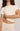 A close-up of a model wearing a short-sleeve ribbed crop top and matching pants in a warm off-white color, both featuring a small scattered cartoon cat print.