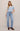 Woman wearing a light blue top and jeans on a plain background