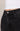 Close-up of black jeans with a button detail on a neutral background