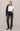Woman wearing a white t-shirt, black jeans, and a black leather jacket on a beige background