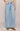 Person wearing light blue wide-leg jeans on a beige background