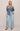 Woman wearing a denim shirt and light blue jeans against a beige background