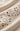 Close-up of a cream-colored fabric with delicate floral eyelet embroidery and cutout detailing.