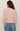 Person wearing a pink sweater and blue jeans on a plain background