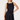 A blonde model wearing a sleeveless black satin mini dress with gold shoulder embellishments, photographed against a clean white studio background.
